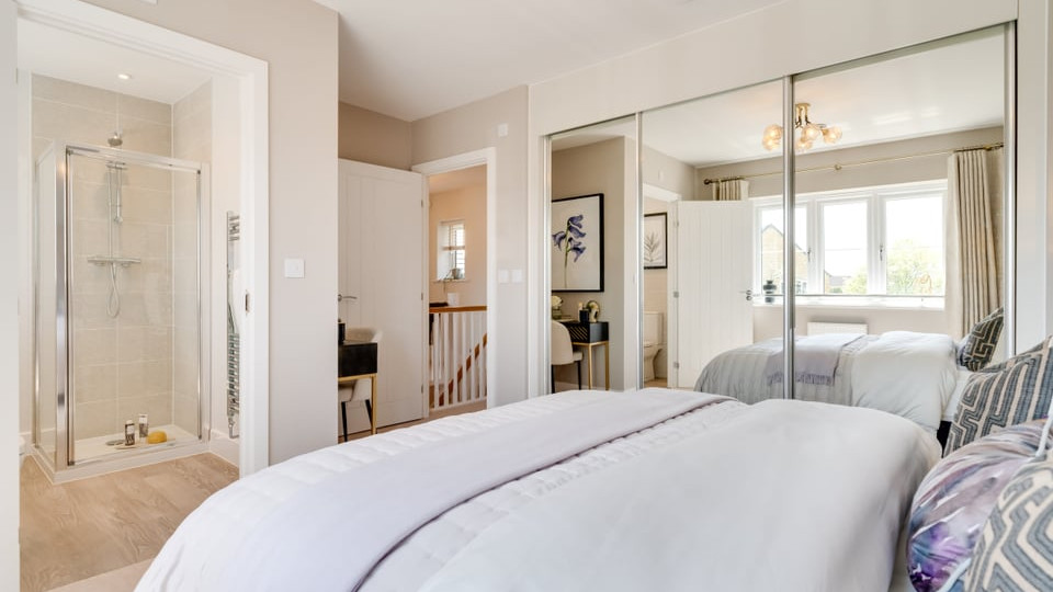 Interior view of double bedroom with mirrored wardrobes, ensuite shower room and view out to the landing.