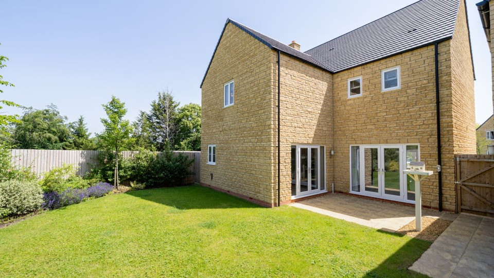 External view of rear garden, rear view of home with Cotswold brick and two sets of French doors.