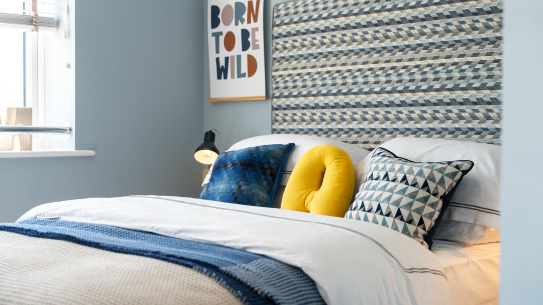 Bedroom with double bed next to a window featuring a patterned headboard