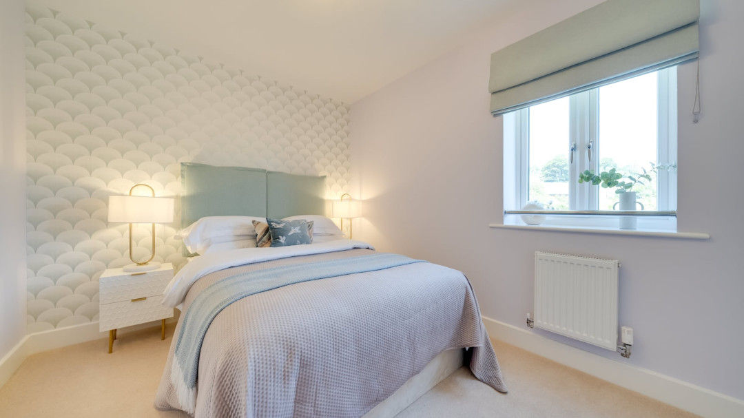Bedroom with a double bed against a mint green patterned feature wall