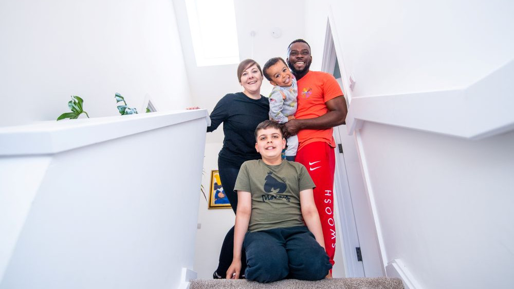 a couple and their children smiling while stood in their stairway